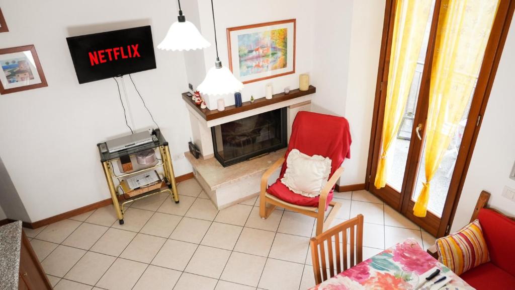 salon z czerwonym krzesłem i kominkiem w obiekcie Panoramic lake view home's Giulia w mieście Casasco Intelvi