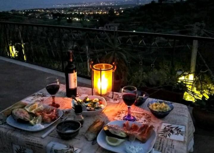 a table with plates of food and wine glasses at Flat with panoramic terrace and private pool mt5x3 in Taormina