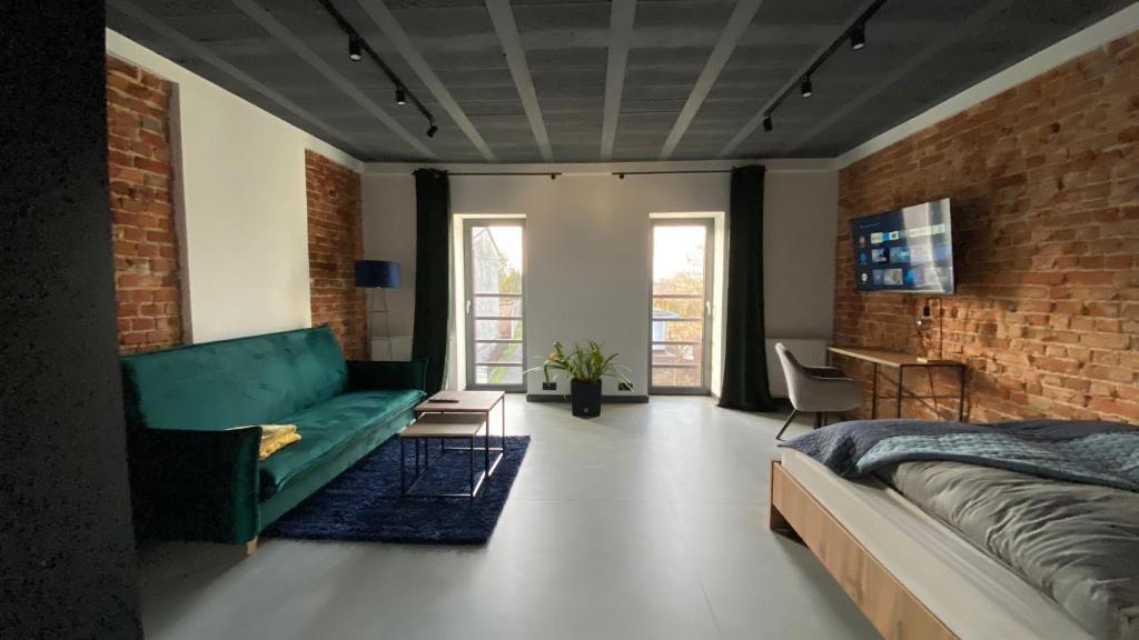 um quarto com um sofá verde e uma parede de tijolos em Apartamenty Gliwice Staromiejska 65 em Gliwice
