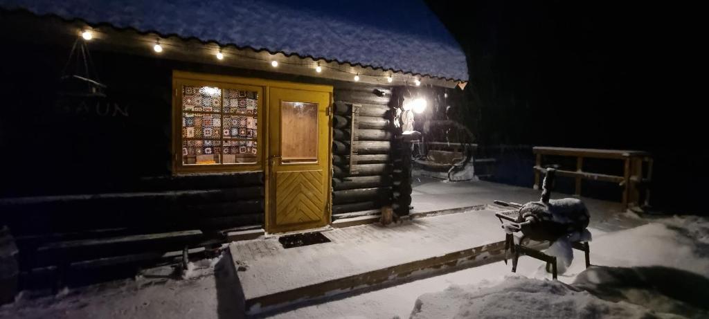 Cabaña de madera con puerta amarilla en la nieve en Atsikivi Puhketalu en Häädemeeste
