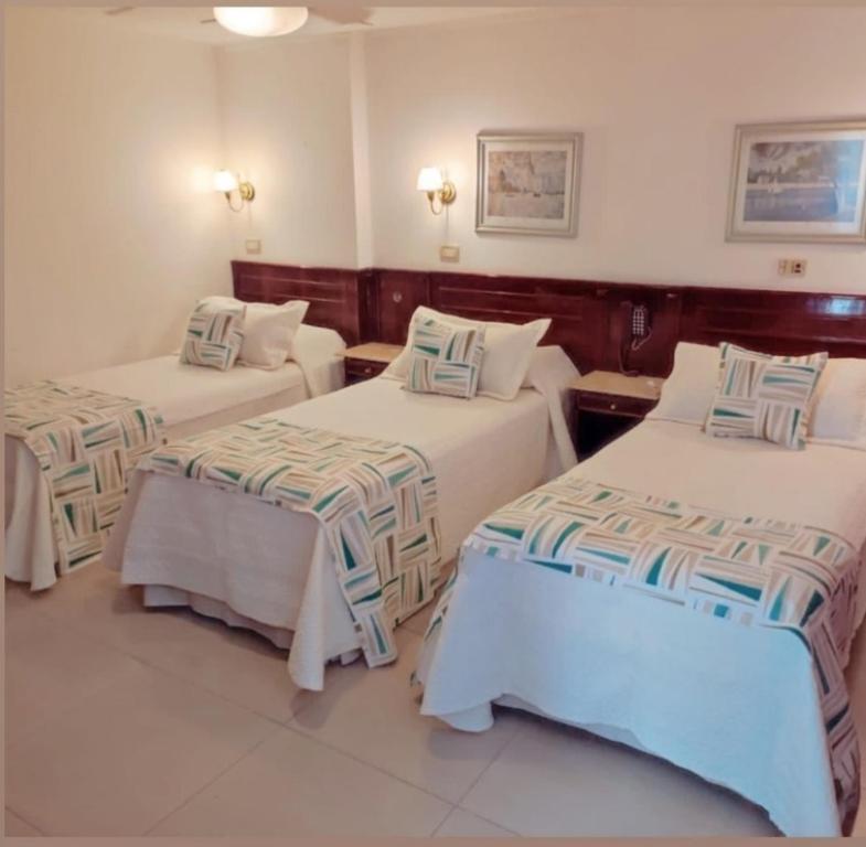 a hotel room with two beds and two tables at HOTEL CASTELAR CORDOBA in Cordoba