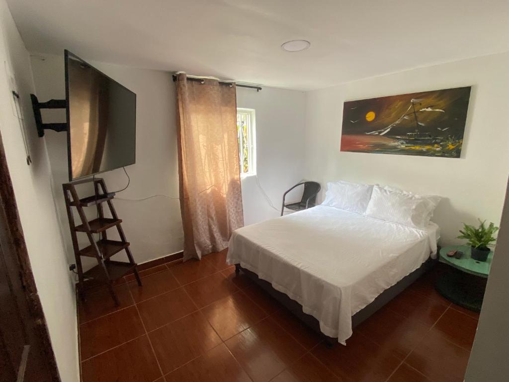 Un dormitorio con una cama blanca y una pintura en la pared en MAGICA CABAÑA EN MEDIO DE LA NATURALEZA en Armenia