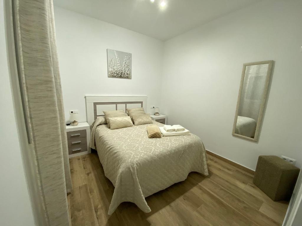 ein weißes Schlafzimmer mit einem Bett und einem Spiegel in der Unterkunft Ático Álvaro in Setenil de las Bodegas