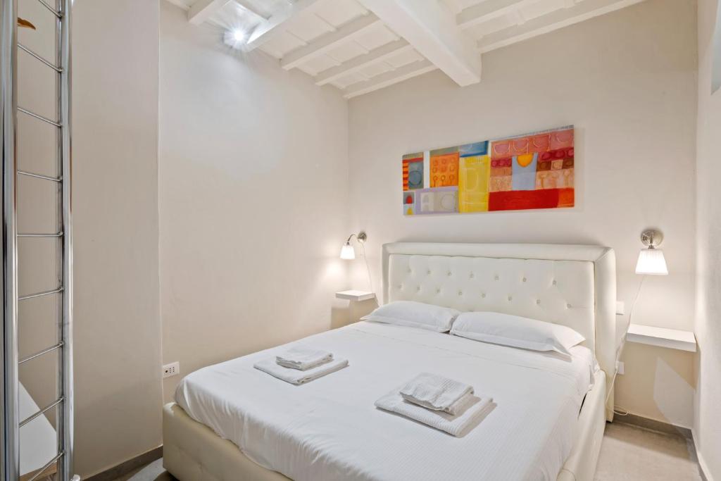 a white bedroom with a white bed with two towels on it at Il Palazzo della Signoria Modern Loft in Florence