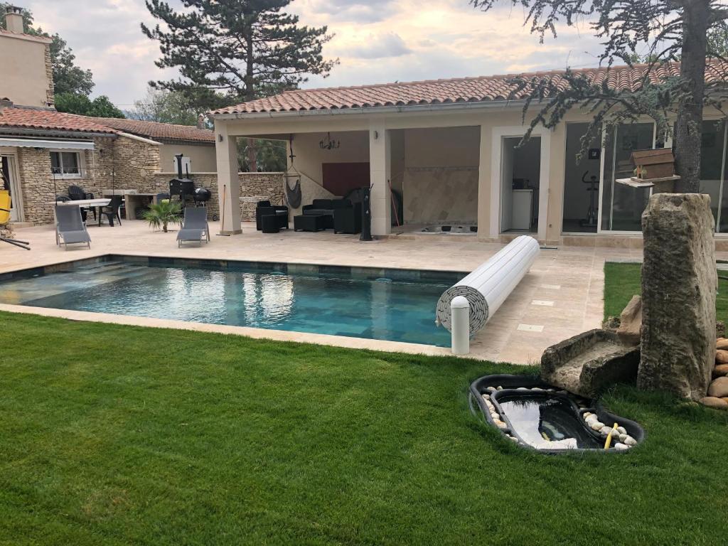 una piscina con un tobogán de agua en un patio en Au milieu des Piboules de Provence. en LʼIsle-sur-la-Sorgue