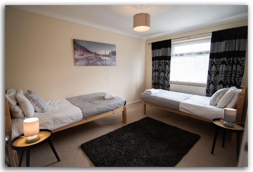 1 dormitorio con 2 camas y ventana en BridgeCity Spacious Bartok House in the Heart of Basingstoke en Worting