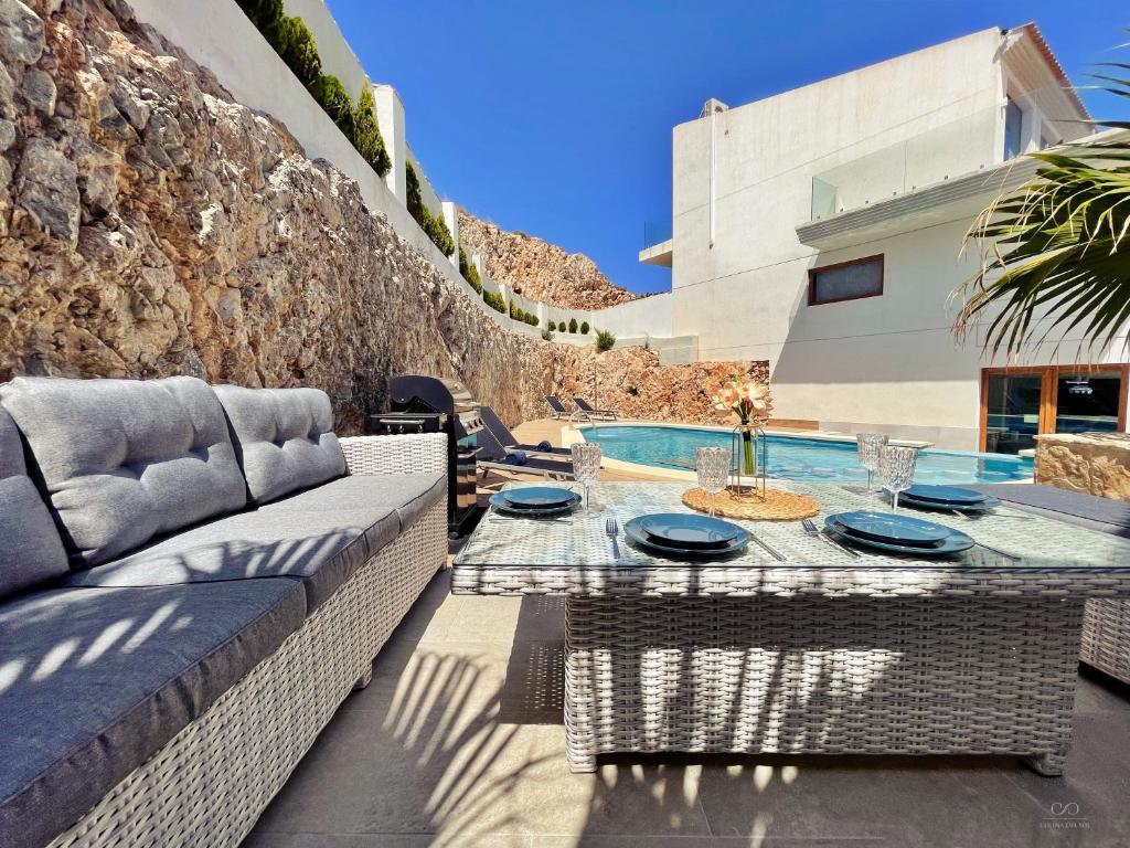 eine Terrasse mit einem Sofa, einem Tisch und einem Pool in der Unterkunft Colina del Sol Cullera - Villa Sol in Cullera