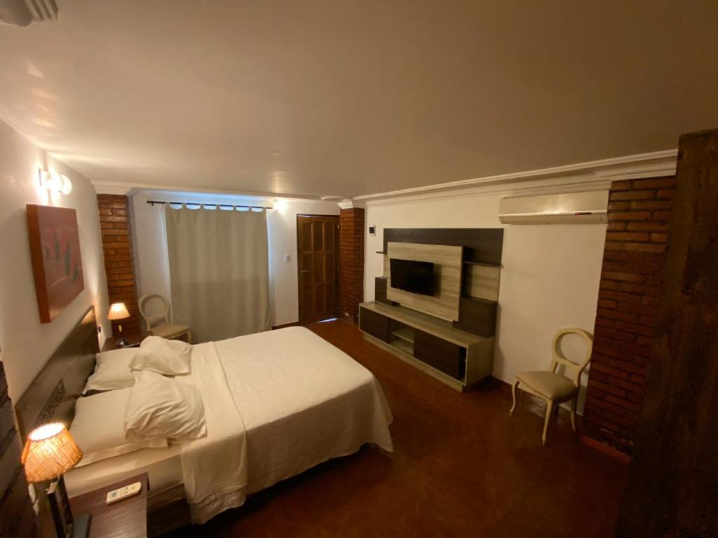 a hotel room with a bed and a television at Boutique Hotel De La Fonte & Restaurant in Puerto Iguazú
