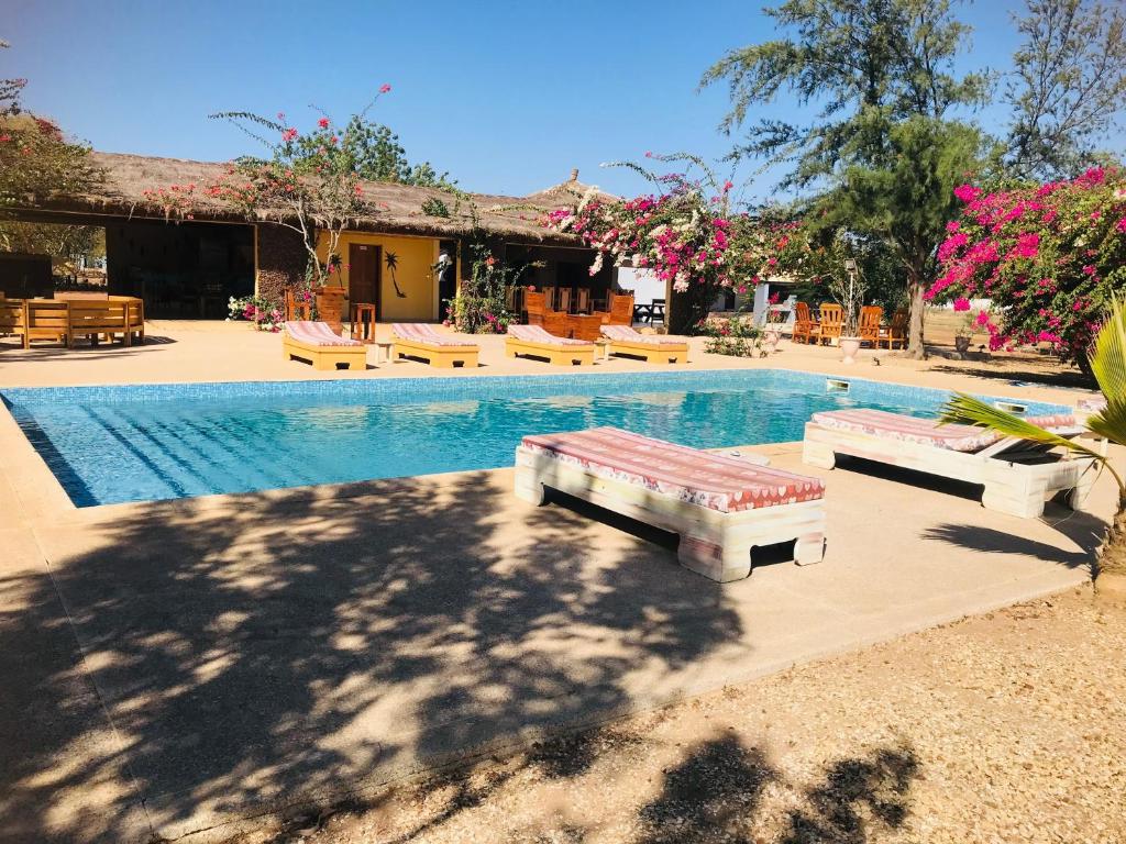 a swimming pool with tables and benches next to a house at Lodge Kabacoto in Nioro du Rip