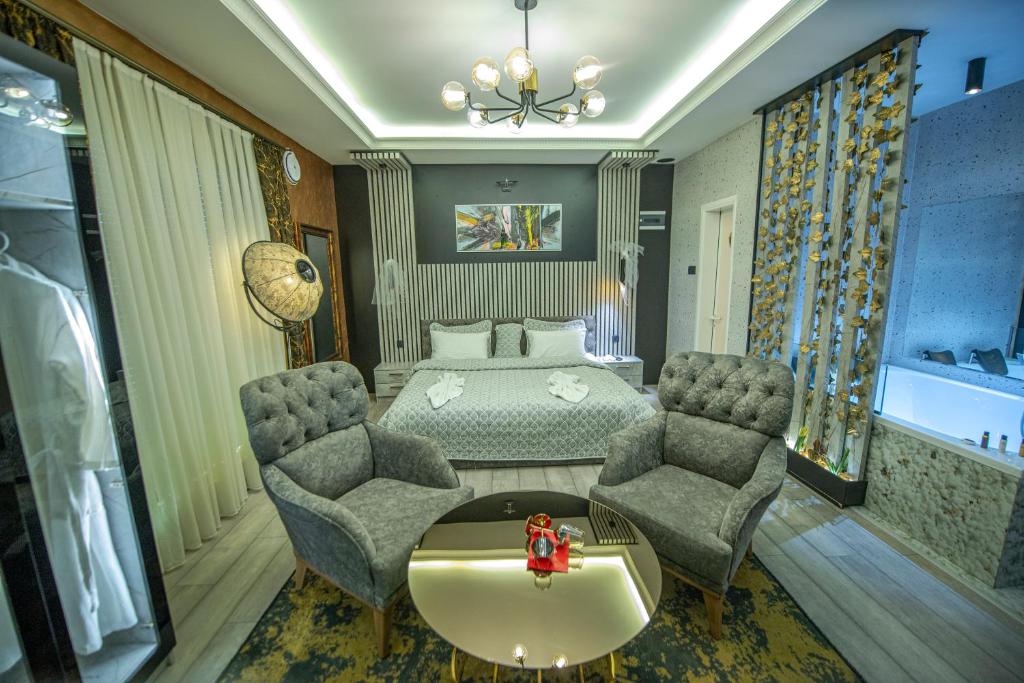 a bedroom with a bed and two chairs and a table at Hotel and Apartments Central City Prishtina in Prishtinë