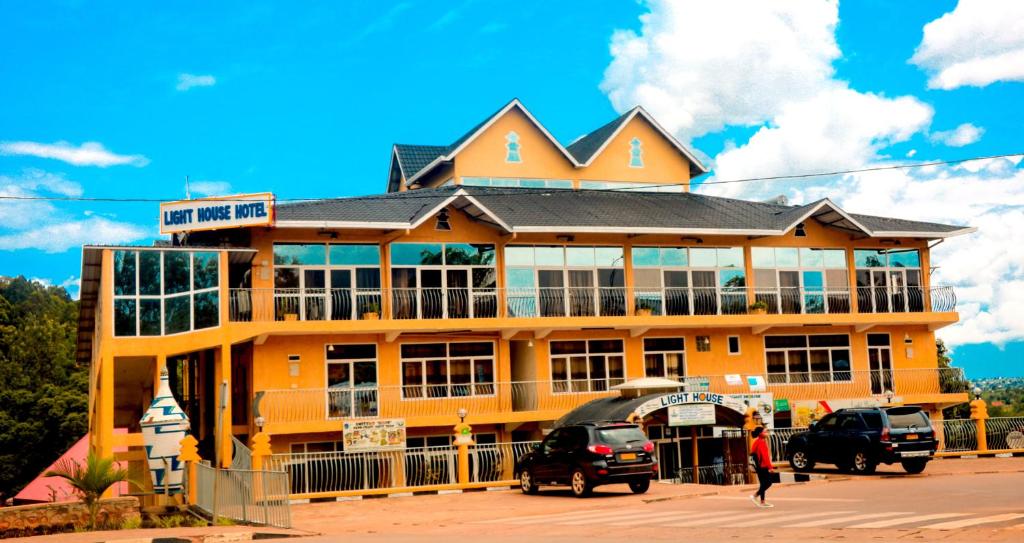 a yellow building with cars parked in front of it at Light House Hotel in Huye