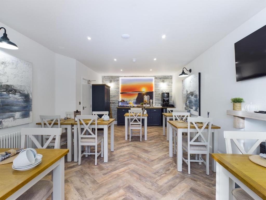 a restaurant with tables and chairs and a kitchen at Driftwood Boutique Guest House in Rhosneigr
