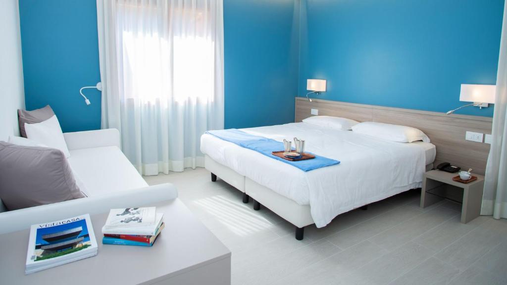 a bedroom with a large white bed and a couch at Hotel President in Lignano Sabbiadoro