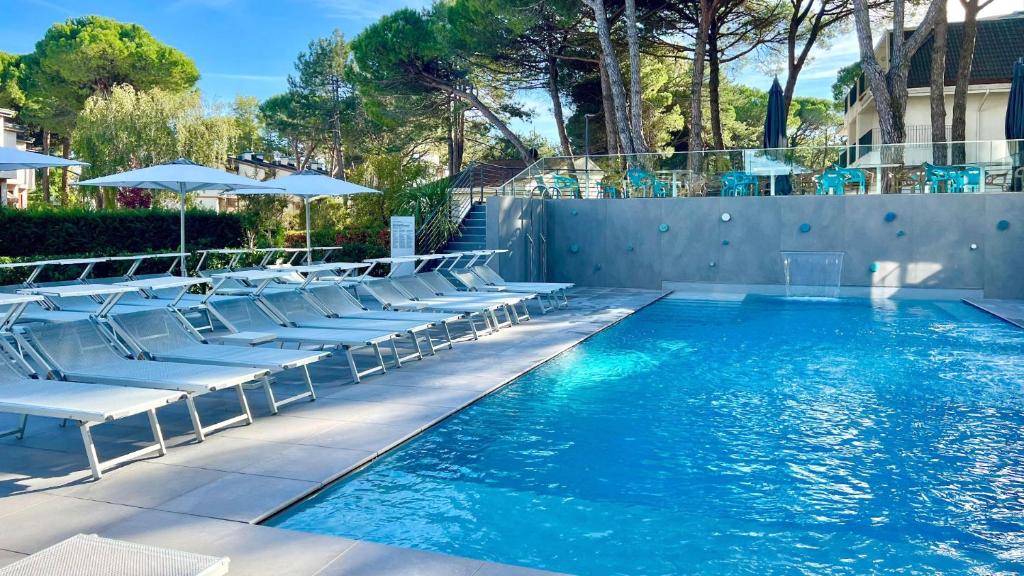 a swimming pool with lounge chairs and a swimming pool at Hotel President in Lignano Sabbiadoro