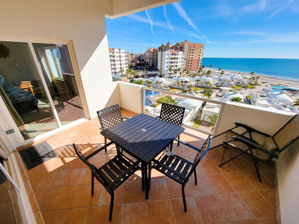 Las Palmas Resort Condo 603 with amazing sea view في بورتو بيناسكو: طاولة وكراسي على شرفة مطلة على المحيط