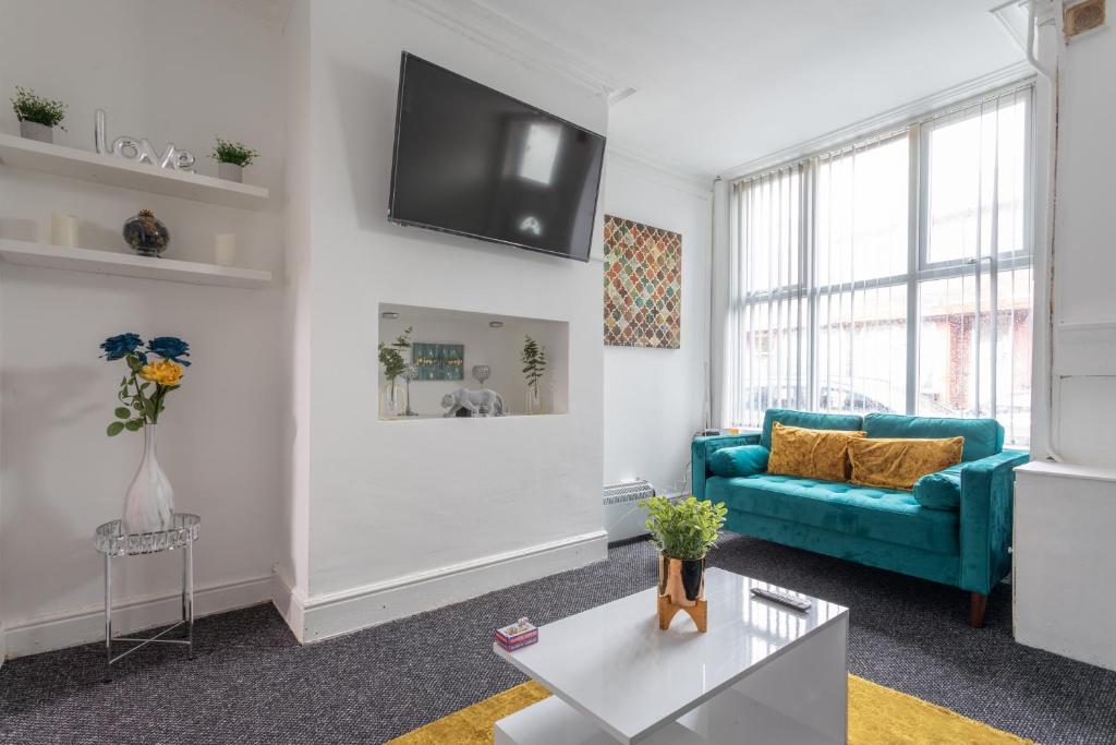 a living room with a blue couch and a tv on the wall at Home in Levenshulme, Manchester in Manchester