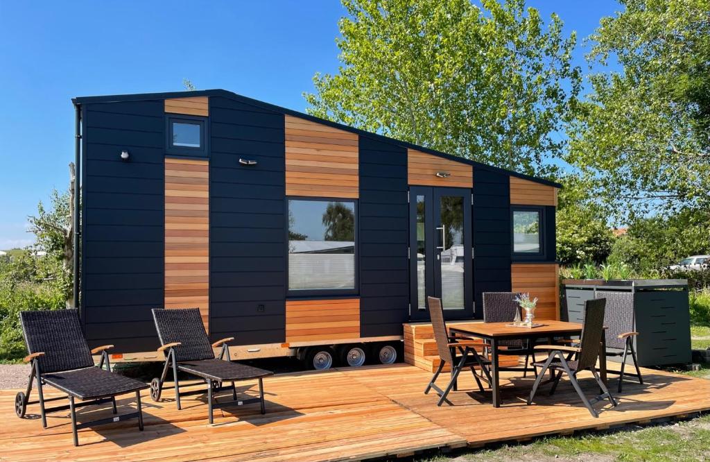 una casita en un remolque con una mesa y sillas en Tiny House Max, en Fedderwardersiel