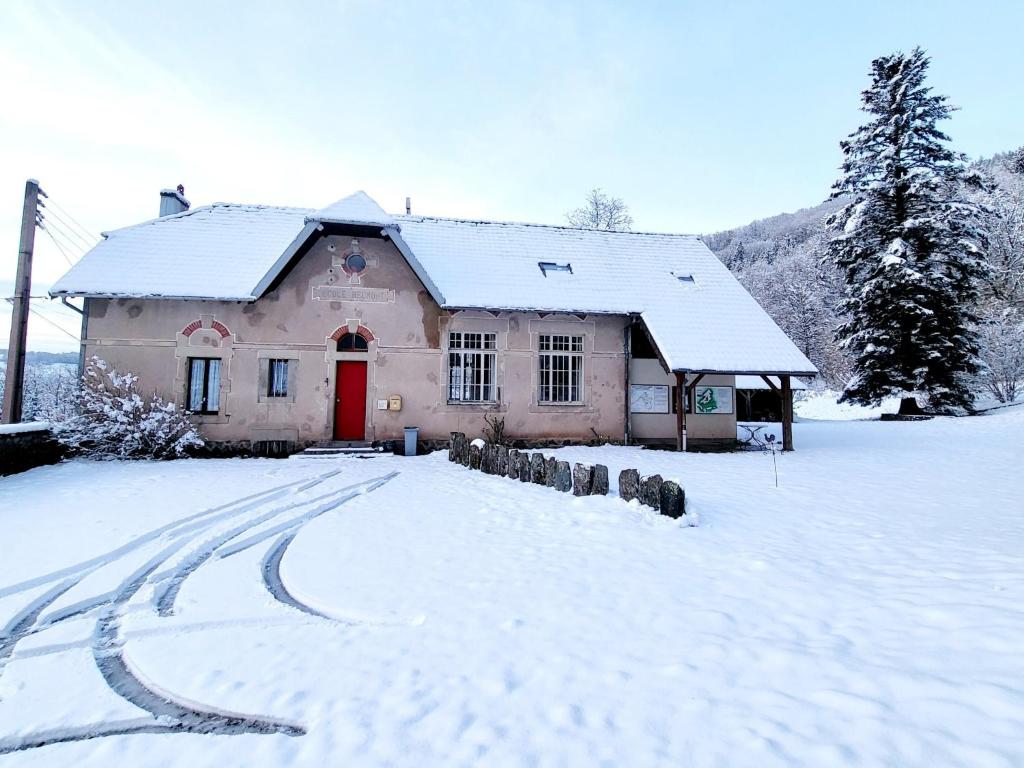 a house with a red door in the snow at ECOLE de BELMONT in Le Haut-du-Them