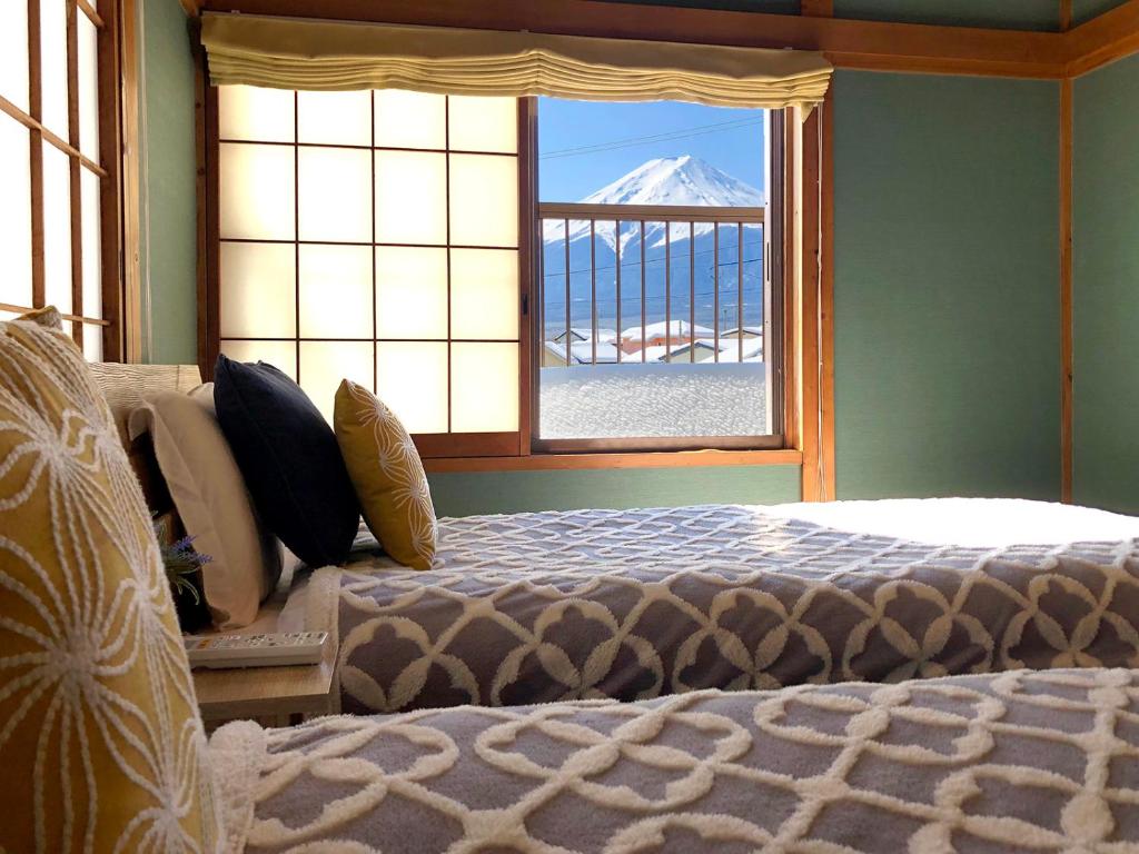 Un dormitorio con una cama y una ventana con una montaña en OriOri House Hotel Mt Fuji view 全室富士山ビューの貸切り宿 折々 en Fujikawaguchiko