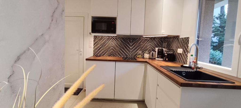 une cuisine avec des armoires blanches, un évier et un micro-ondes dans l'établissement Magnifique T2 centre ville 5 min à pieds des Arènes de Nîmes, à Nîmes