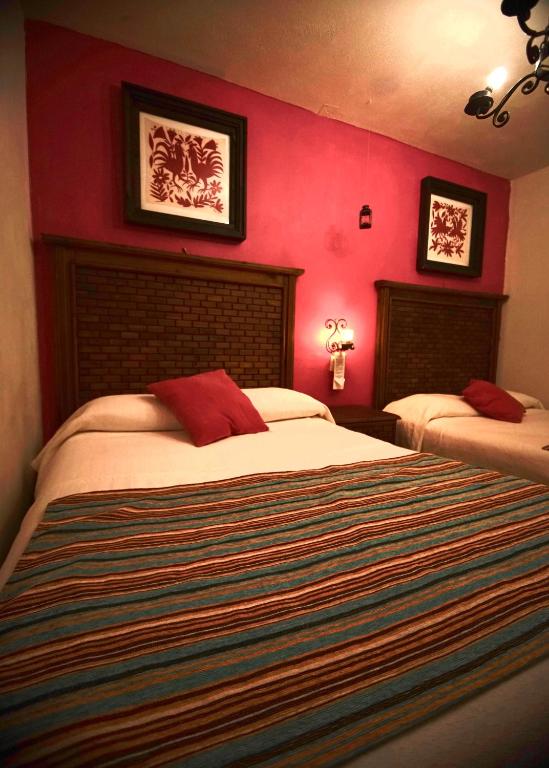 a bedroom with two beds with red walls at La Escondida Hotel Boutique in Zacatlán