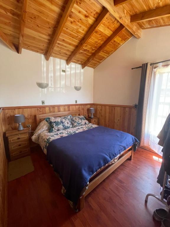 1 dormitorio con 1 cama en una habitación con techos de madera en Cabaña en Licanray, en Villarrica