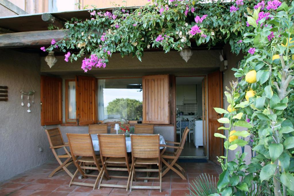 een patio met een tafel, stoelen en bloemen bij Smeralda in Cugnana