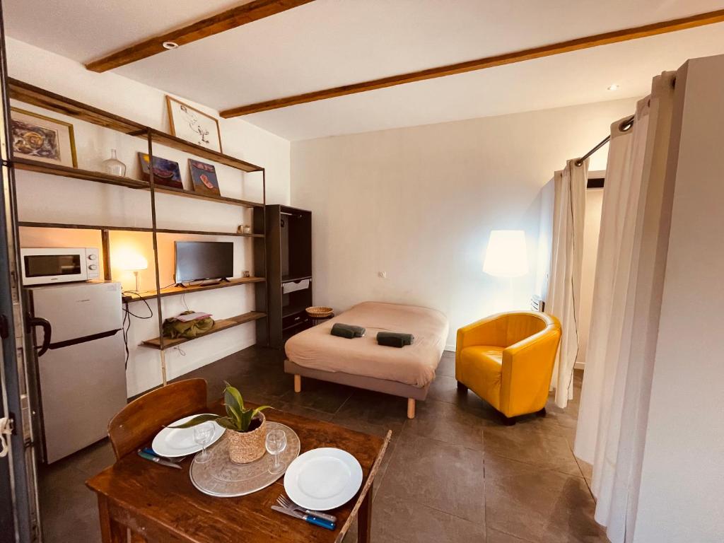 a small room with a table and a yellow chair at Charmant studio loft - Mas Bois Fontaine in Nîmes