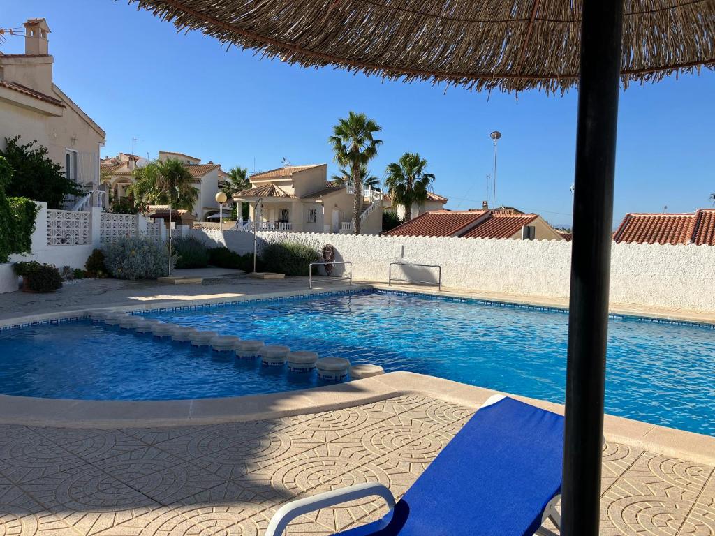 een zwembad met een rieten parasol naast een huis bij Villa South in Ciudad Quesada