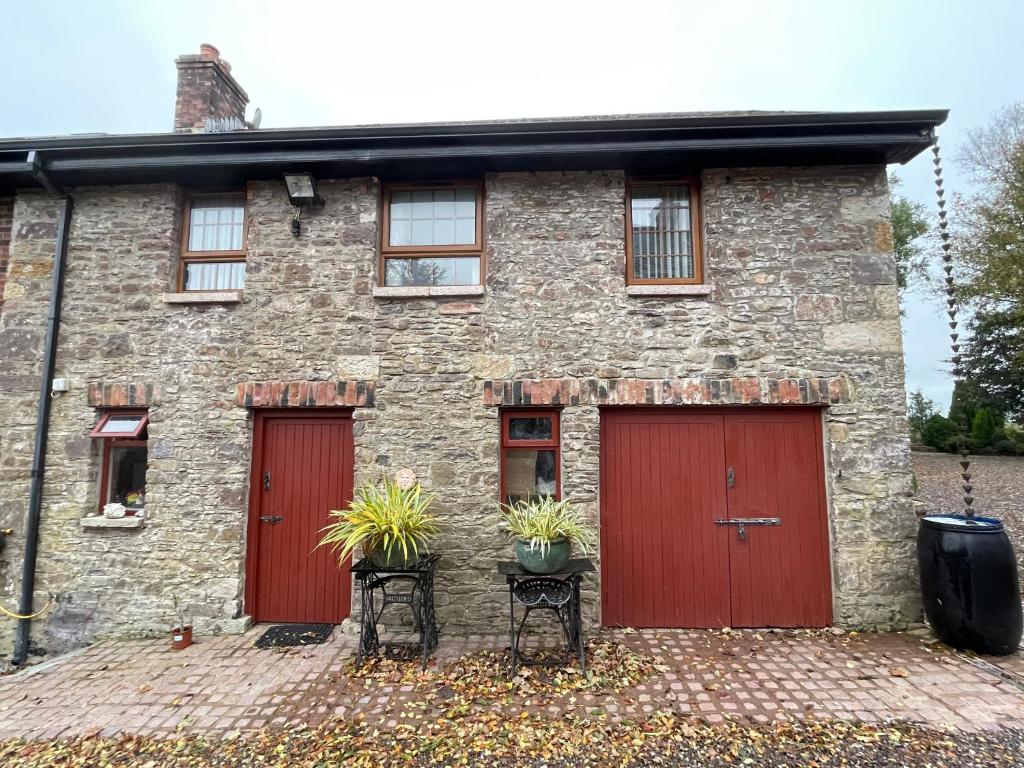 a brick house with two red doors and two chairs at The Slates Apartments - Fuchsia & Orchard Apartments in Irvinestown