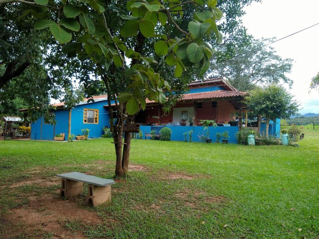 una casa blu con una panchina sotto un albero di Pousada Sítio São Pedro a Delfinópolis