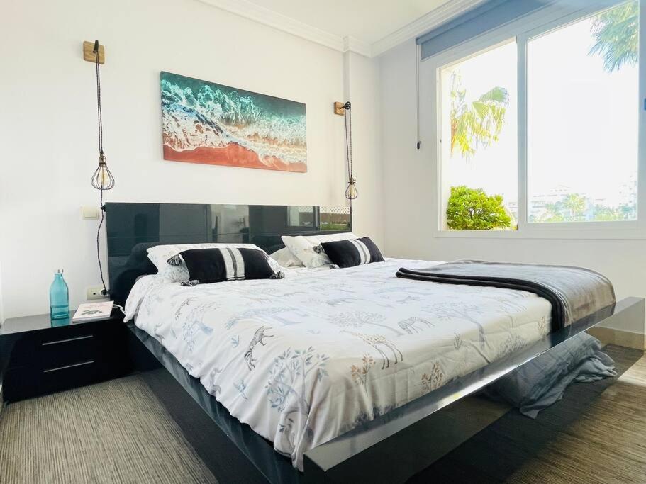 - un grand lit dans une chambre avec une grande fenêtre dans l'établissement Blue Palm Apartment Estepona, à Estepona