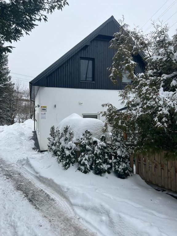 dom ze śniegiem na ziemi obok płotu w obiekcie Apartamenty Slowianka w mieście Wolibórz