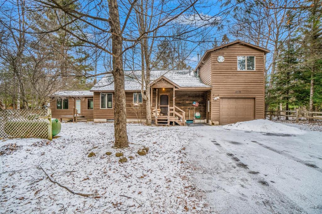 a log home with a tree in the snow at The River Retreat in Thompsonville