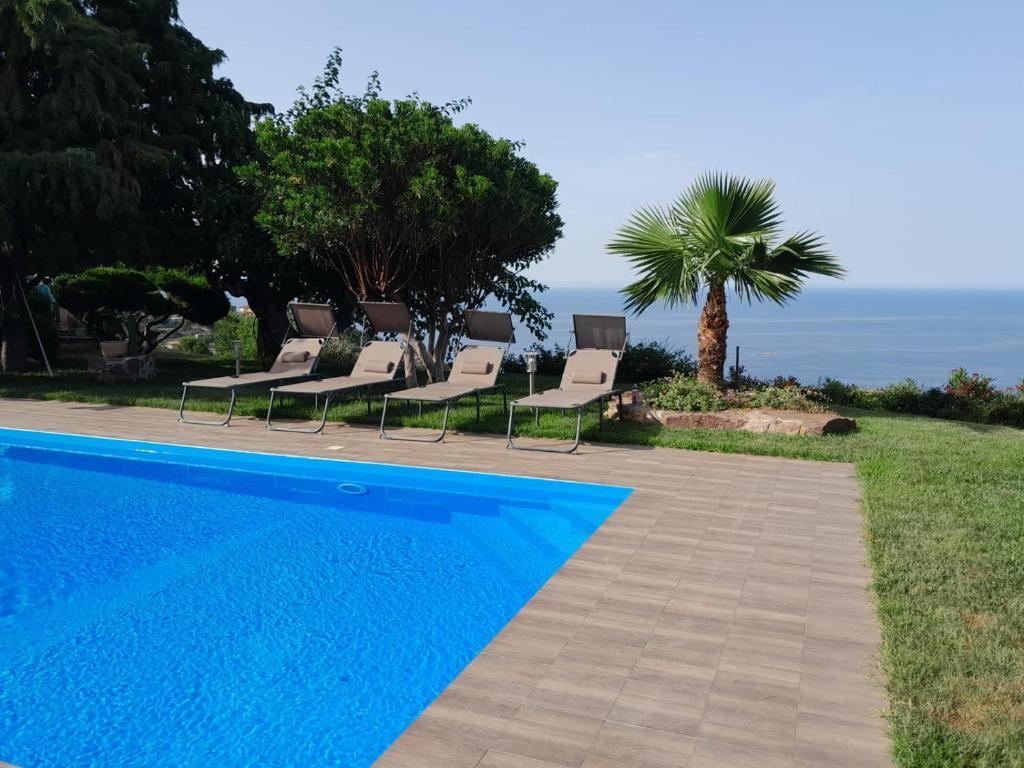 una piscina blu con sedie e una palma di A Casa di Matilde a Gioiosa Marea