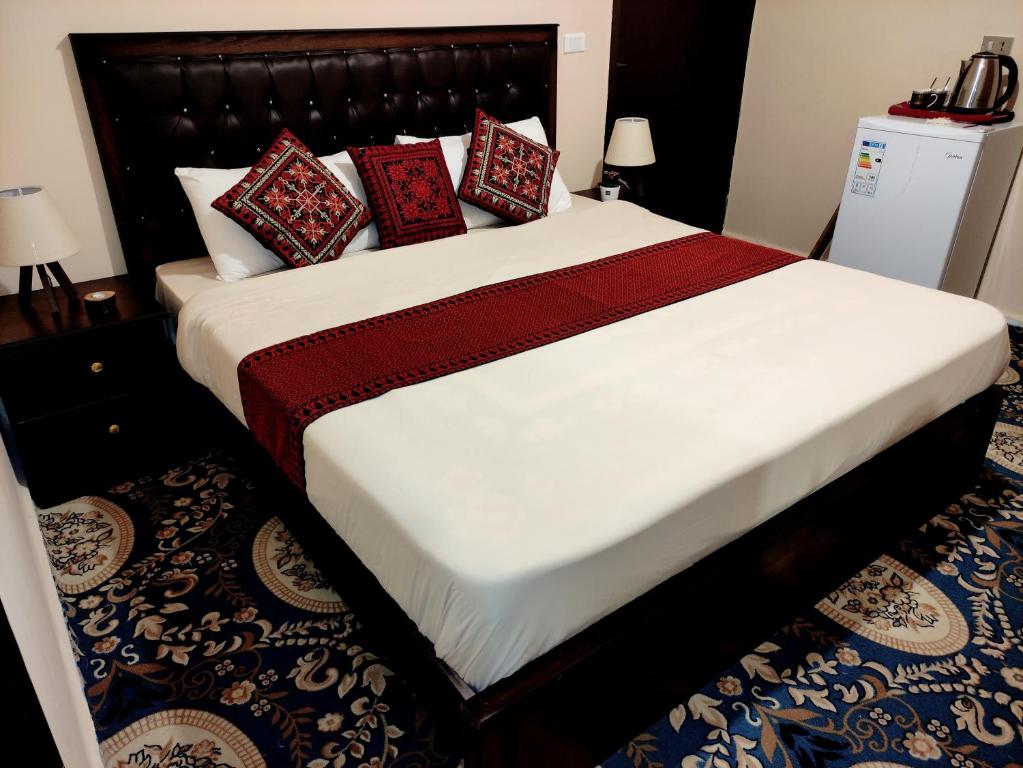 uma cama com almofadas vermelhas num quarto em Majido Hotel em Wadi Musa