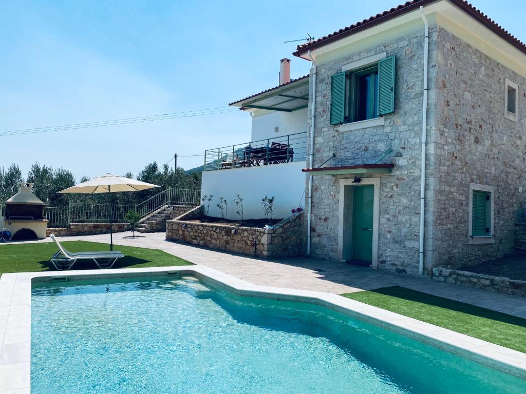 a villa with a swimming pool in front of a house at Appartement Villa Pasithea in Xiropigado