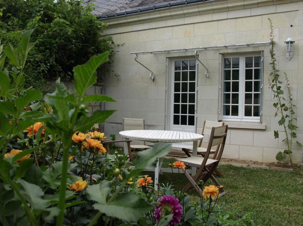 Les gîtes de la Madeleine في La Chapelle-sur-Loire: طاولة وكراسي في حديقة بها زهور