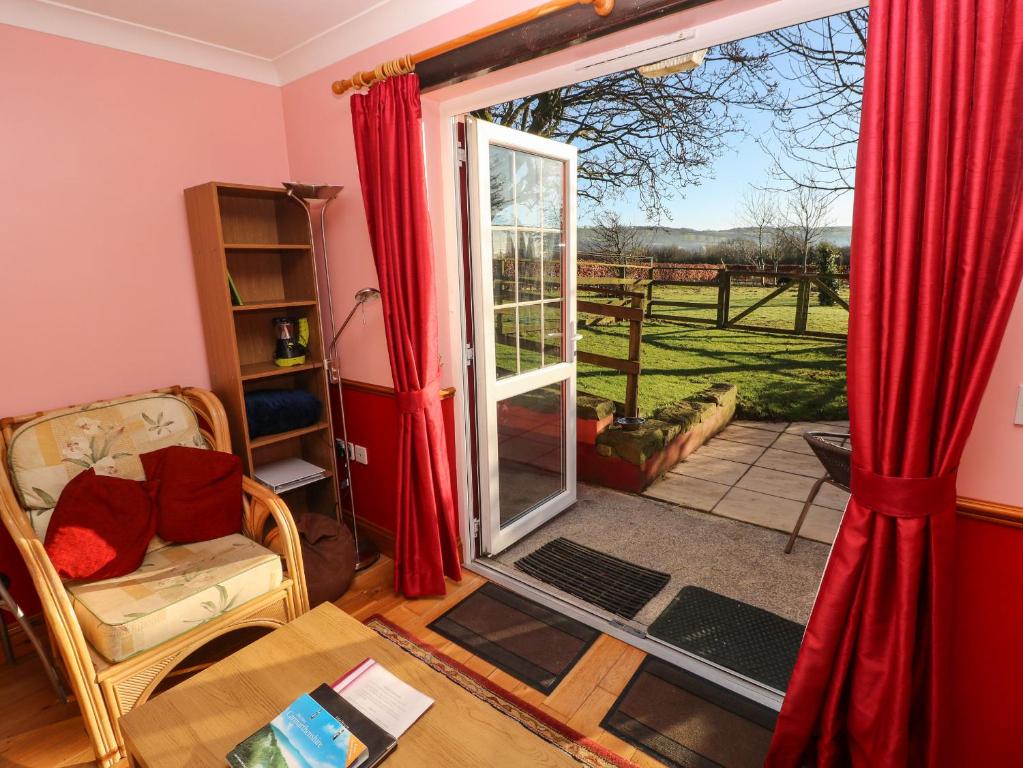 a living room with red curtains and a sliding glass door at Cwtch Cowin in Banc-y-felin