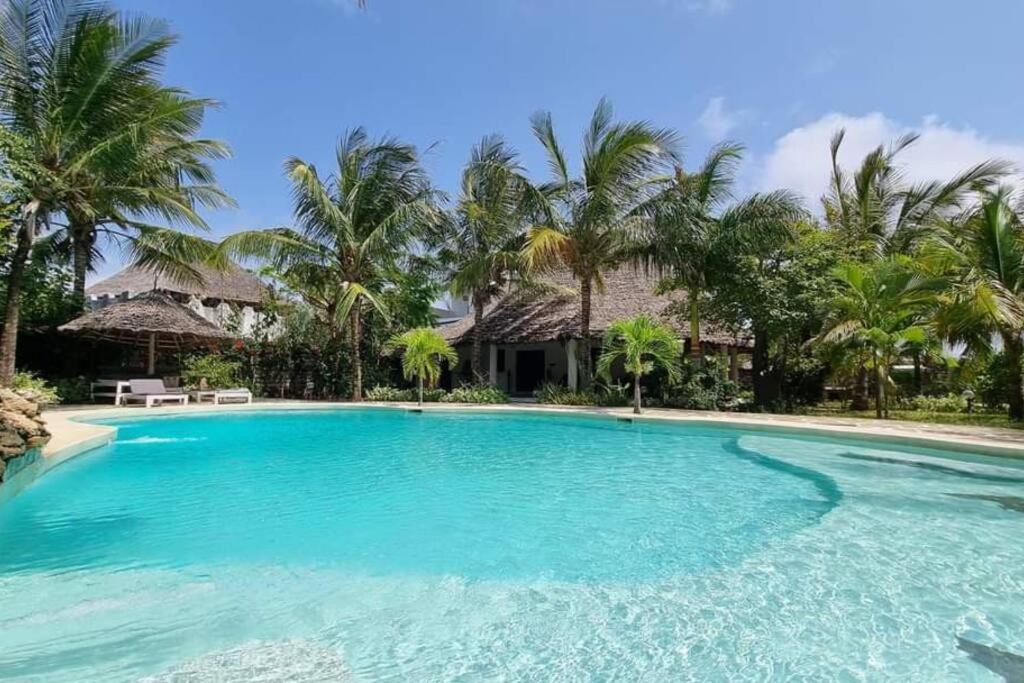 una piscina di fronte a una casa con palme di Luxury Simba House in Watamu [ ☆☆☆☆☆ ] a Watamu