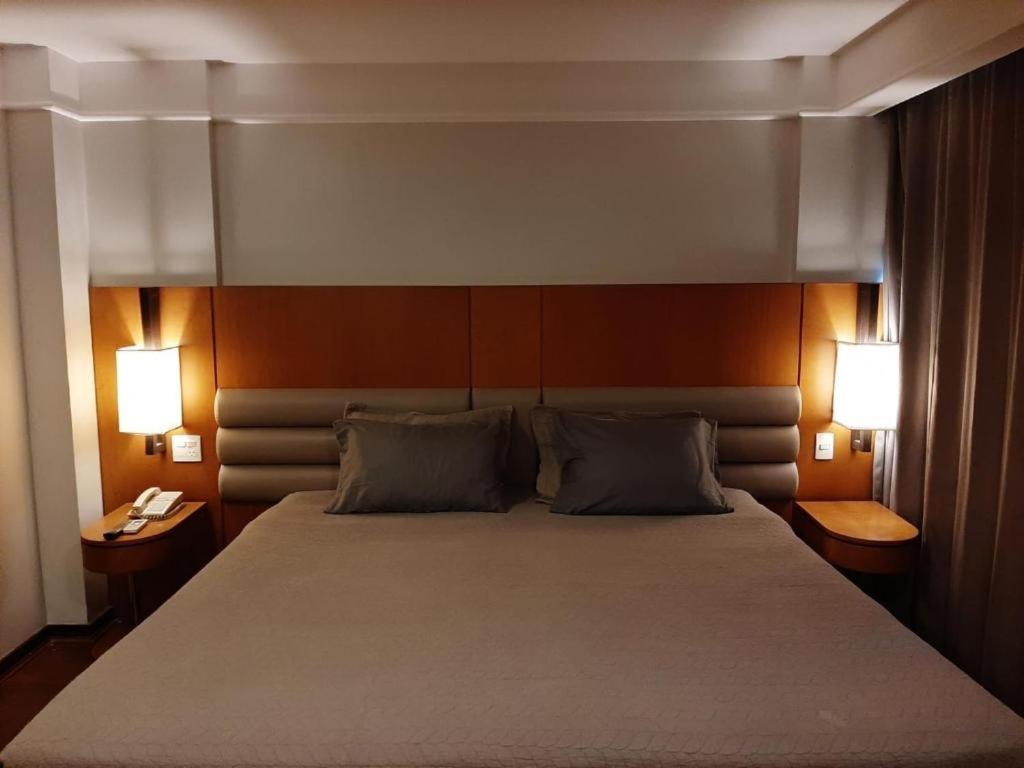 1 dormitorio con 1 cama grande y 2 lámparas en Ótima Localização, reformado e com piscina!, en Río de Janeiro