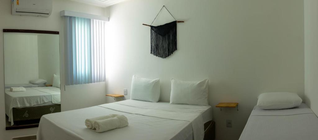 a white bedroom with two beds and a window at Além dos Sonhos in Cayru
