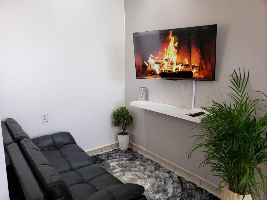 sala de estar con sofá y TV en la pared en Departamentos L en Cuauhtémoc