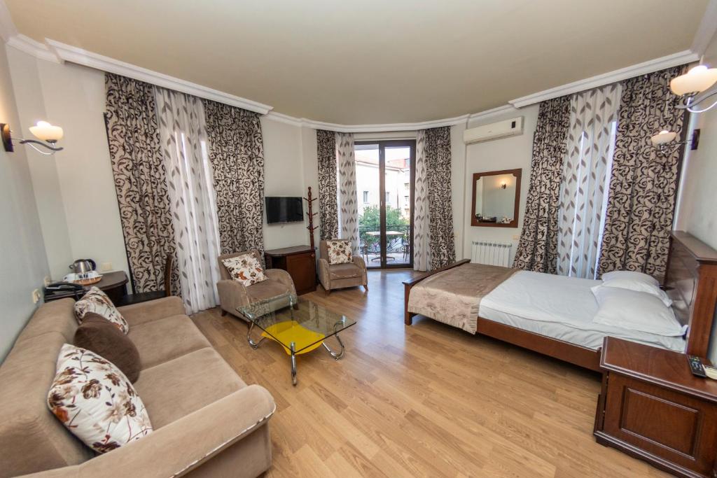 a bedroom with a bed and a couch and a tv at Eiffel Hotel in Batumi