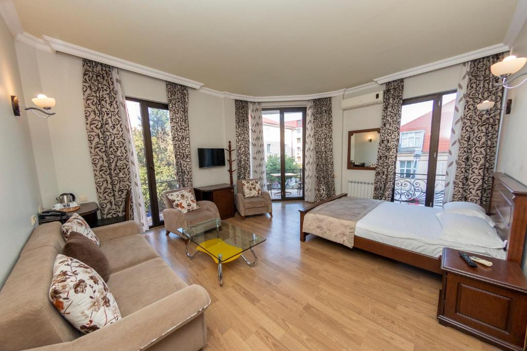een grote slaapkamer met een bed en een bank bij Eiffel Hotel in Batoemi