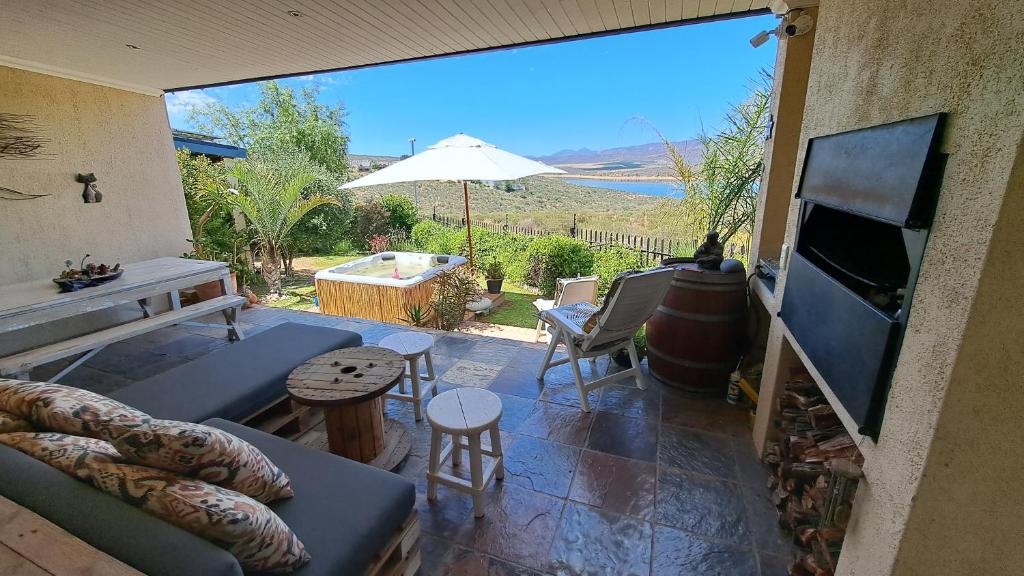 a patio with a couch and a television and a table at Clanwilliam Oasis - Naturism, Boating, Hiking & more in Clanwilliam