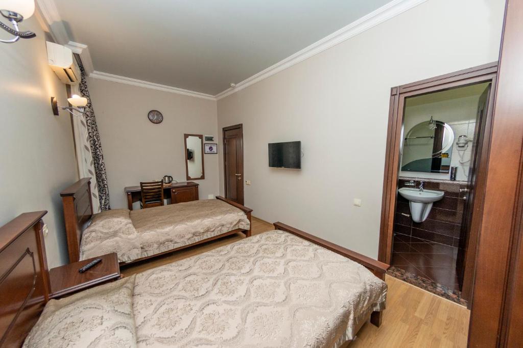 a hotel room with two beds and a sink at Eiffel Hotel in Batumi