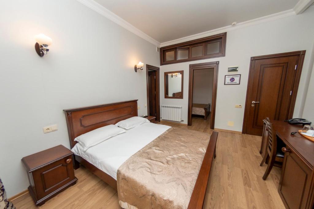 a bedroom with a large bed and a desk at Eiffel Hotel in Batumi