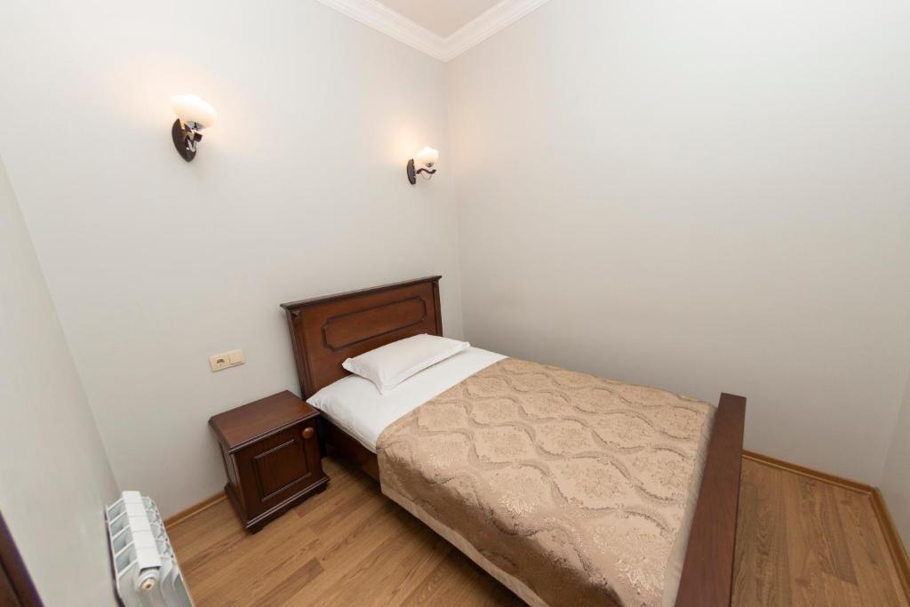 a small bedroom with a bed and a night stand at Eiffel Hotel in Batumi