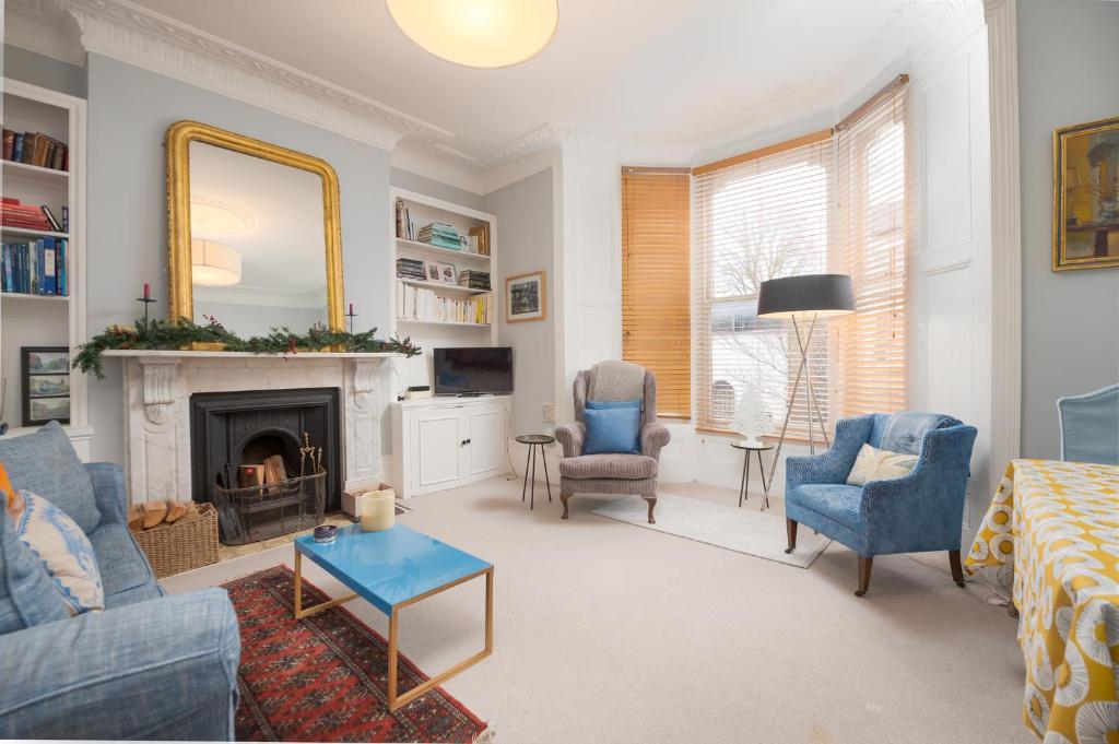 a living room with a fireplace and blue chairs at Charming flat in leafy West London by UnderTheDoormat in London